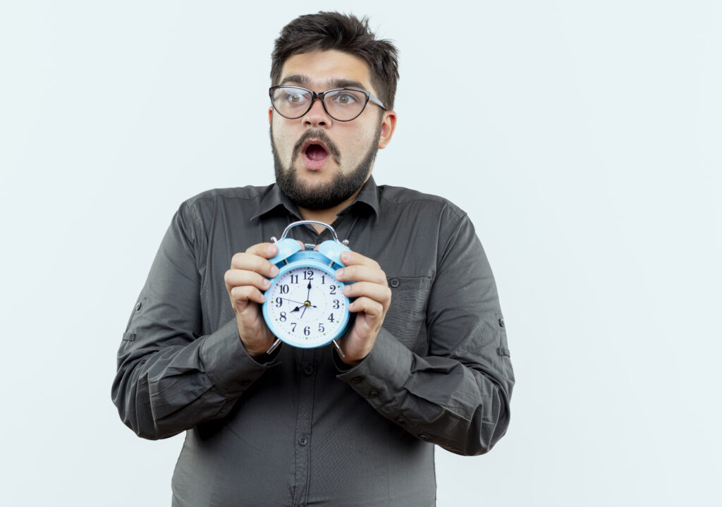 Worried businessman holding an alarm clock symbolizing the risks of rushing background checks.